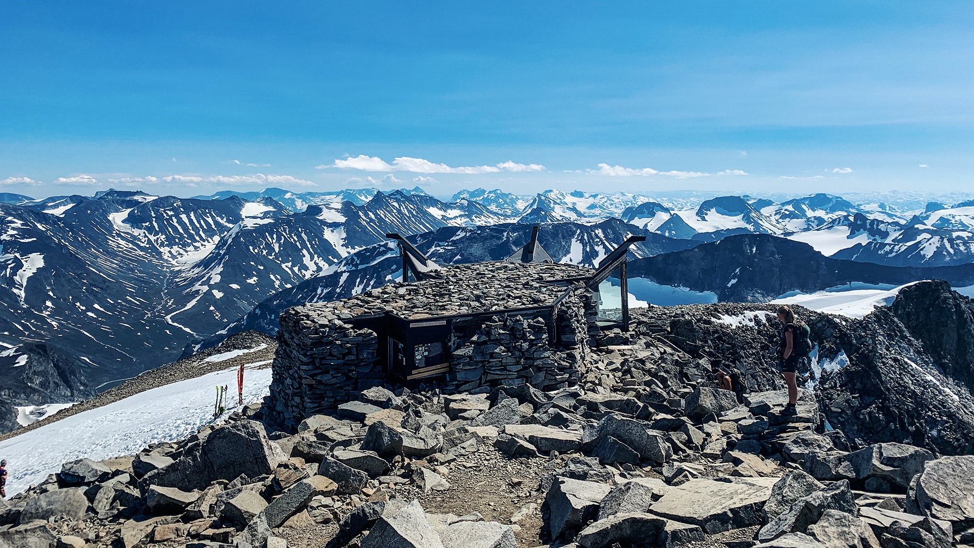 The stone cafe at the top on Galdhøpiggen with tall mountain tops in the distance.