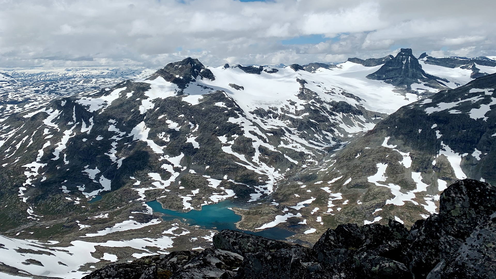 A small lake surrounded by the snow covered tall mountain tops of Rauddalstindane.