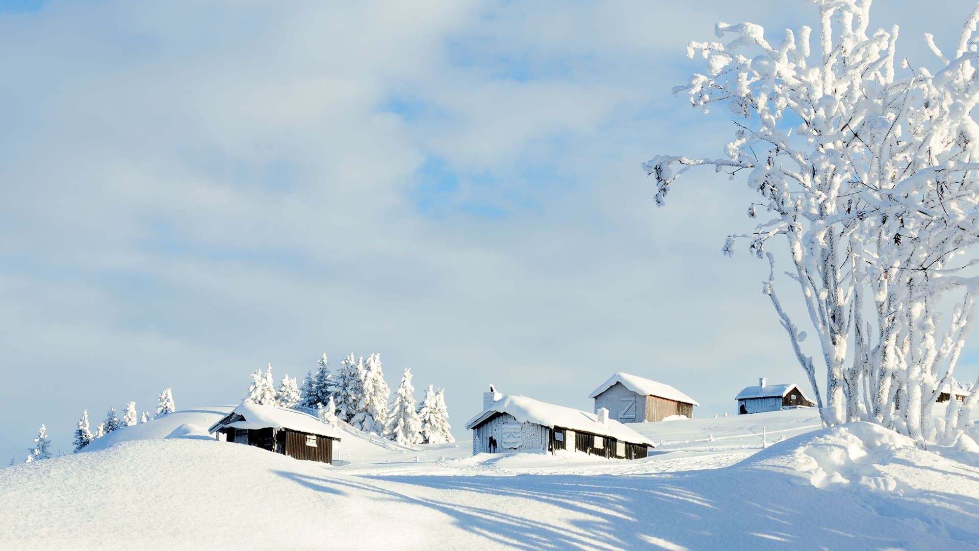 Wooden buildings with snow covered rooftops on a hill at Hafjell.