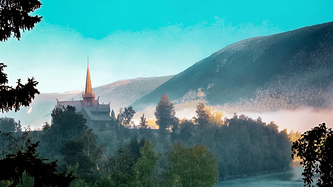 The stave church of lom covered in moring mist at sunset.