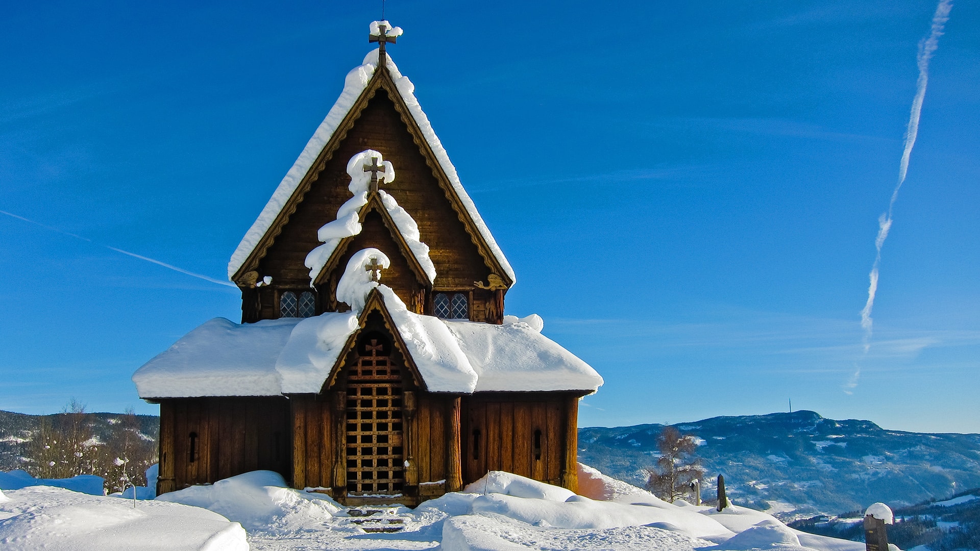 The stave church of Reinli covered in snow on a sunny winter day.