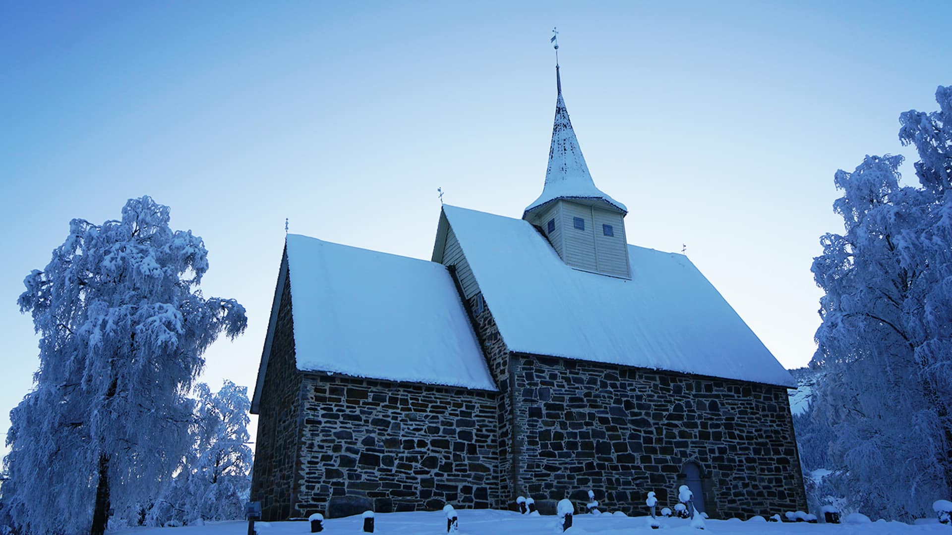 The medieval church of Slidredomen with a snow covered roof in wintertime.