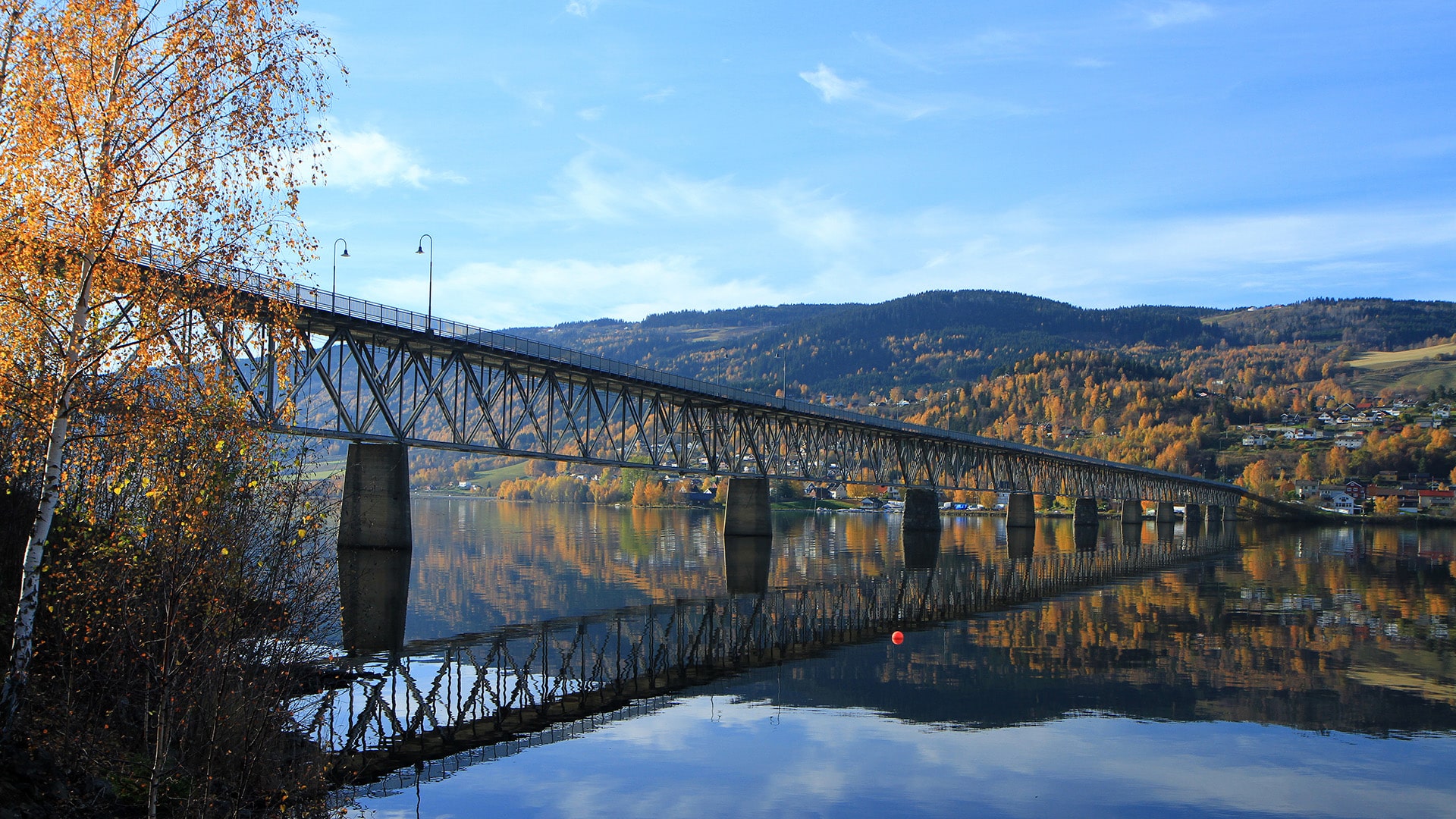 The bridge of Vingnes reflecting in lake Mjøsa on a suny autumn day.