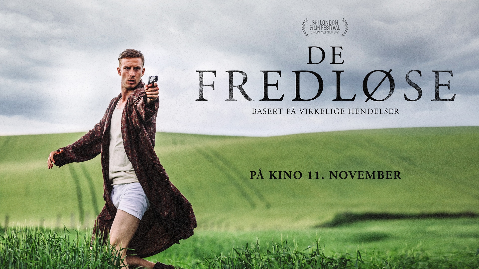 A man pointing a gun wearing a robe on the promotional poster for movie De Fredløse.