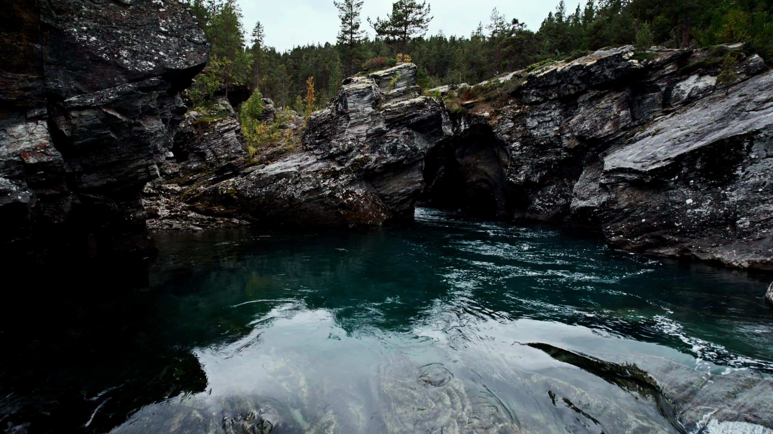 Clear blue water is flowing through a natural stone cave.