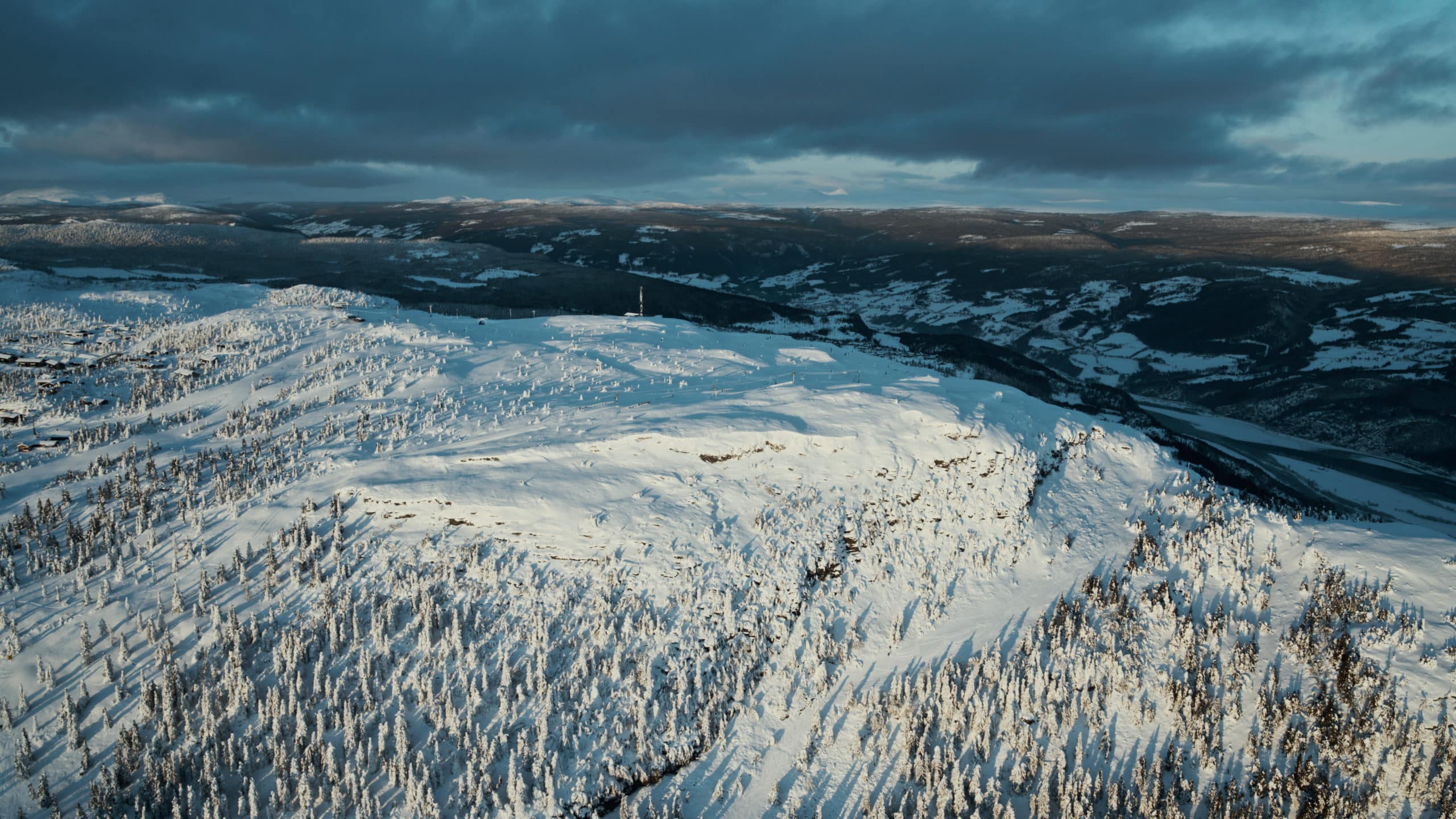 View of Kvitfjell mountain covered by snow and trees with a low hanging sun.