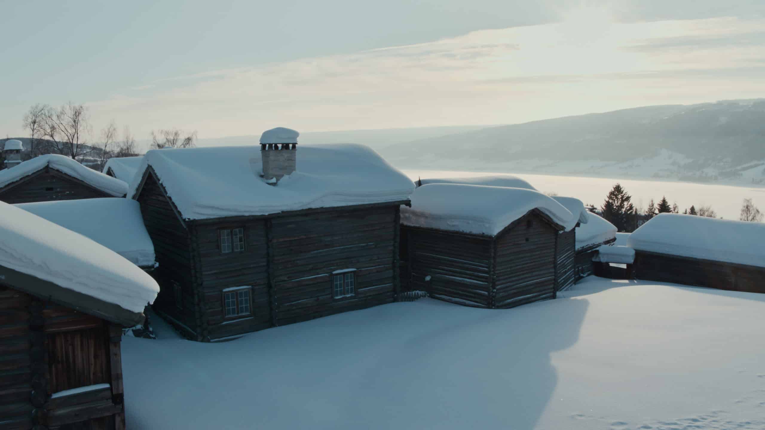 Traditional Norwegian laft wood buildings covered in snow at Maihaugen museum.
