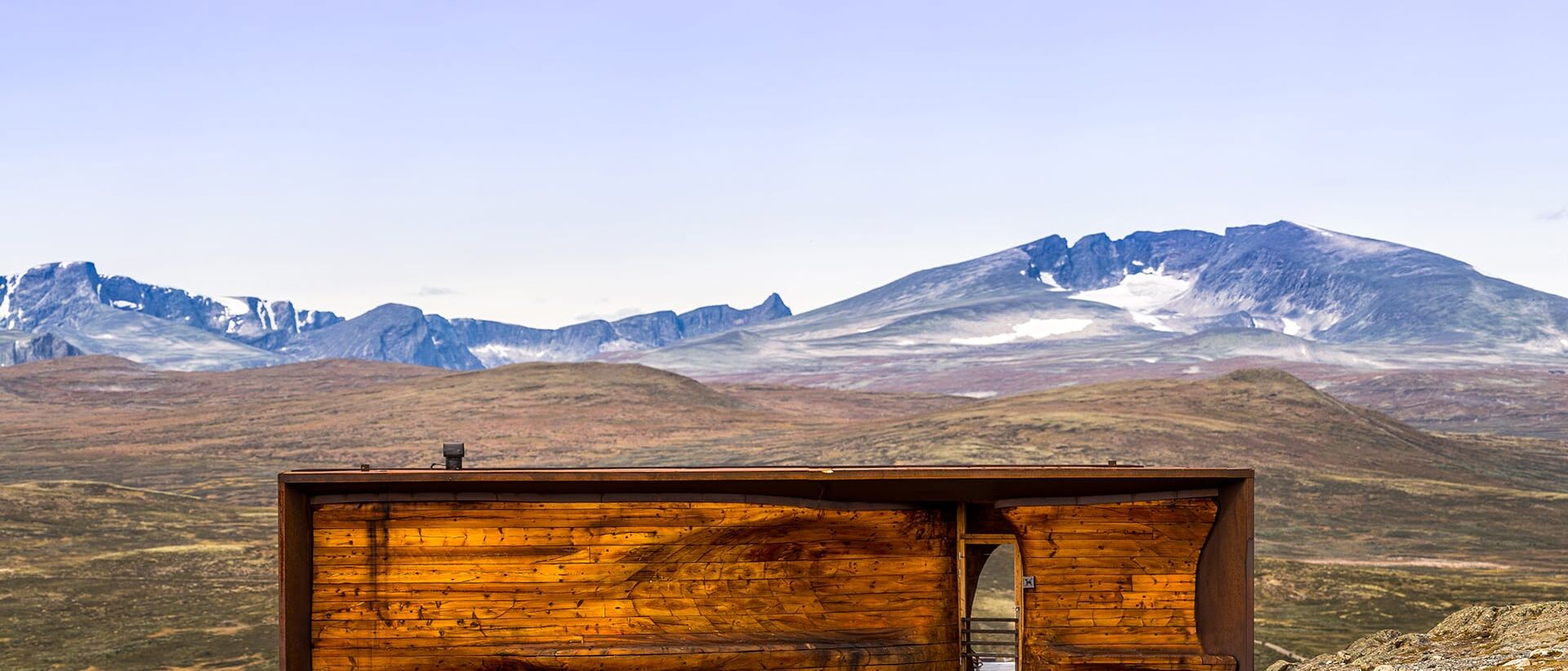 Wild Reindeer Pavilion. A wooden building in front of snow covered mountain Snøhetta on Dovrefjell.